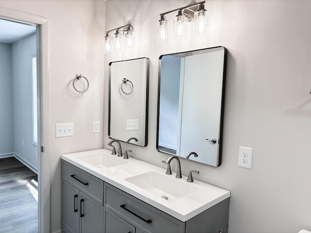 bathroom featuring double vanity, wood finished floors, and baseboards