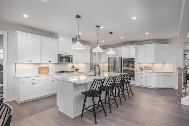 9016 Nestling Ridge Ct, College Grove, TN 37046 - kitchen featuring stainless steel appliances, a sink, wood finished floors, a breakfast bar area, and tasteful backsplash