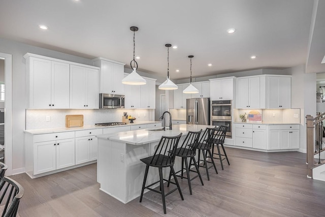 9016 Nestling Ridge Ct, College Grove, TN 37046 - kitchen with stainless steel appliances, a sink, tasteful backsplash, a kitchen breakfast bar, and wood finished floors