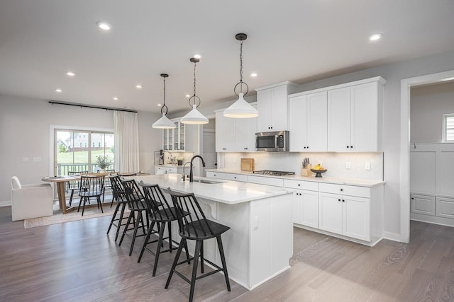 9016 Nestling Ridge Ct, College Grove, TN 37046 - kitchen featuring appliances with stainless steel finishes, a sink, a kitchen island with sink, a breakfast bar, and wood finished floors