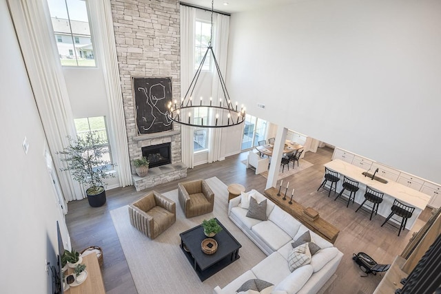 9016 Nestling Ridge Ct, College Grove, TN 37046 - living room with a towering ceiling, healthy amount of natural light, wood finished floors, a chandelier, and a stone fireplace