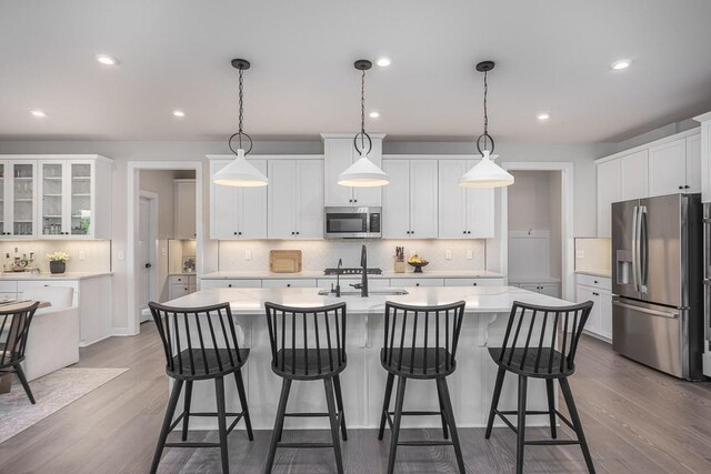9016 Nestling Ridge Ct, College Grove, TN 37046 - kitchen with stainless steel appliances, a sink, light countertops, a center island with sink, and white cabinetry