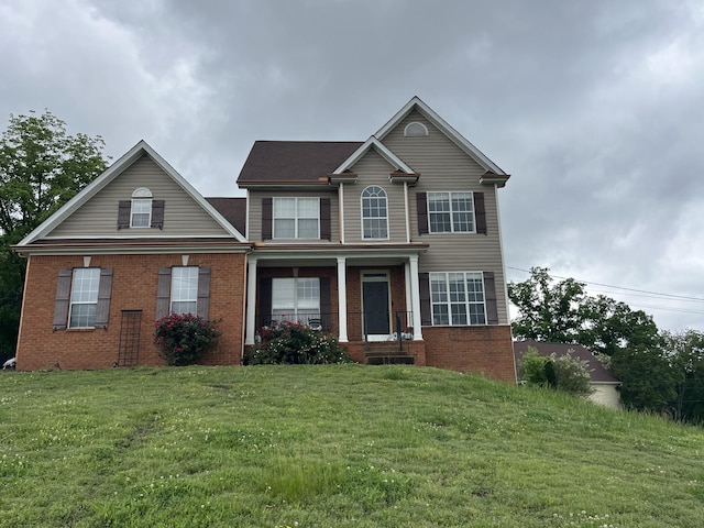 view of front facade featuring brick siding, a front lawn, and a porch