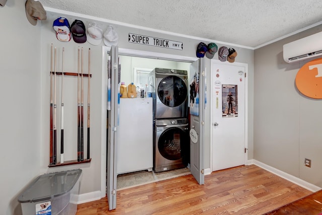 110 Marita Ave, Goodlettsville, TN 37072 - laundry room featuring estacked washer and dryer, a textured ceiling, wood finished floors, a wall mounted AC, and baseboards