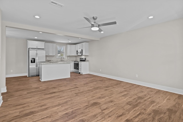 unfurnished living room featuring baseboards, wood finished floors, recessed lighting, a ceiling fan, and a sink