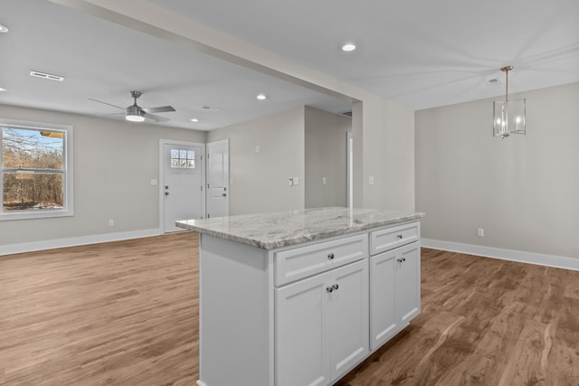 kitchen with light wood finished floors, a kitchen island, baseboards, and recessed lighting