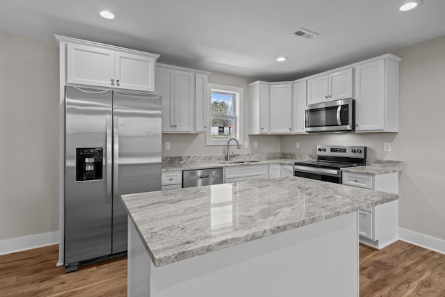 kitchen with appliances with stainless steel finishes, a sink, baseboards, white cabinetry, and recessed lighting