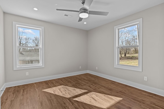 unfurnished room featuring plenty of natural light, wood finished floors, baseboards, and recessed lighting