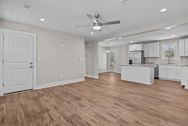 kitchen featuring appliances with stainless steel finishes, a kitchen island, a sink, recessed lighting, and baseboards