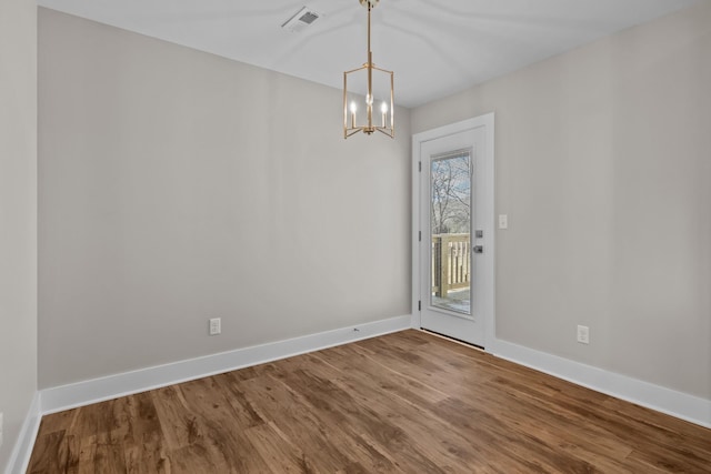 unfurnished dining area with wood finished floors, baseboards, and a chandelier