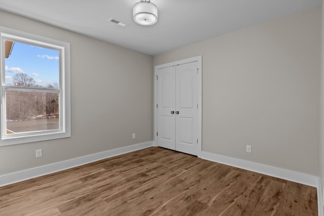 spare room with baseboards and wood finished floors