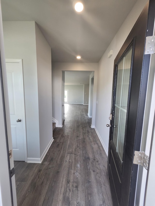 hallway with dark wood-type flooring, baseboards, and recessed lighting