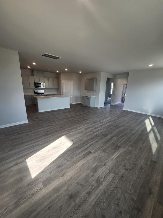 unfurnished living room with baseboards, dark wood-style floors, recessed lighting, and a sink
