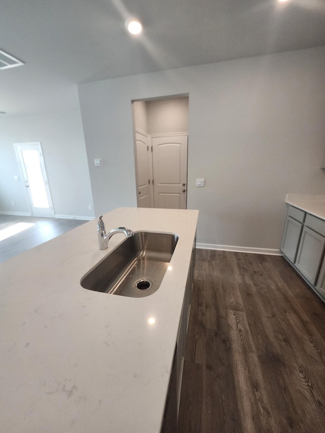 kitchen featuring a sink, dark wood-style floors, gray cabinetry, baseboards, and open floor plan