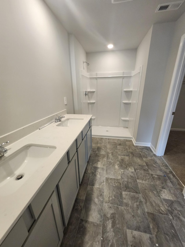 full bathroom featuring a shower, stone finish flooring, a sink, and baseboards