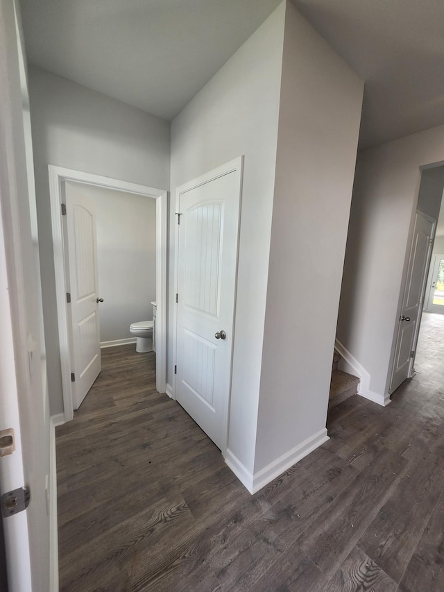 corridor with dark wood-style flooring and baseboards