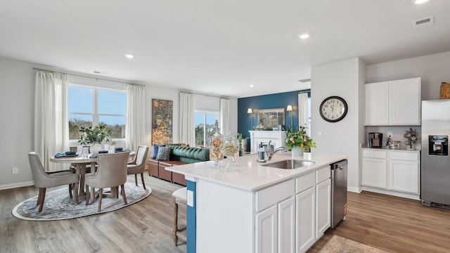 kitchen featuring a sink, appliances with stainless steel finishes, light countertops, open floor plan, and white cabinetry