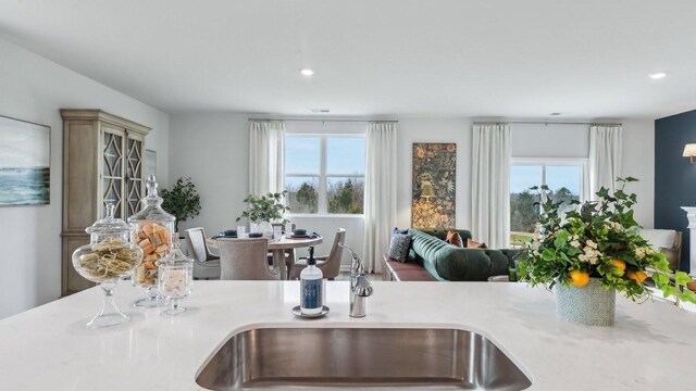 kitchen with a sink, healthy amount of natural light, open floor plan, recessed lighting, and light countertops