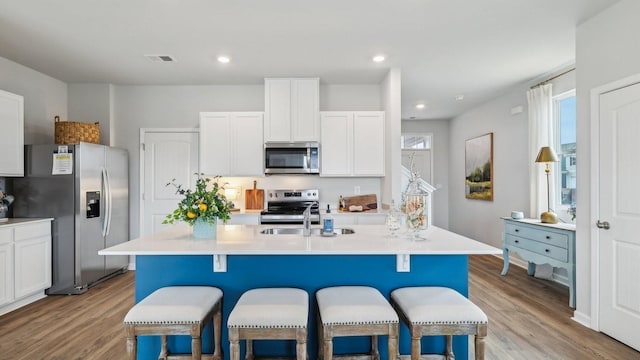 kitchen featuring appliances with stainless steel finishes, light wood-style floors, a breakfast bar area, a sink, and recessed lighting
