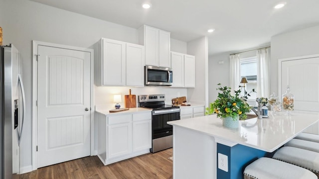 kitchen with stainless steel appliances, a breakfast bar, white cabinets, and recessed lighting