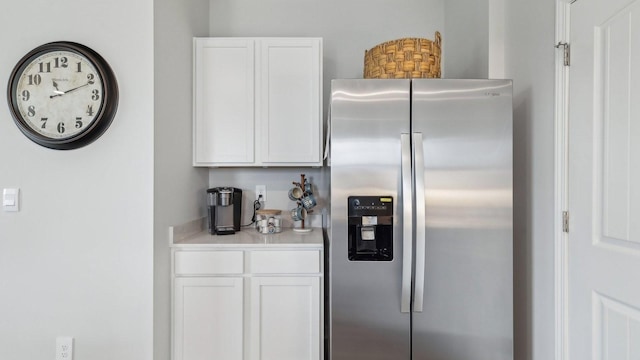 kitchen with stainless steel refrigerator with ice dispenser, white cabinets, and light countertops
