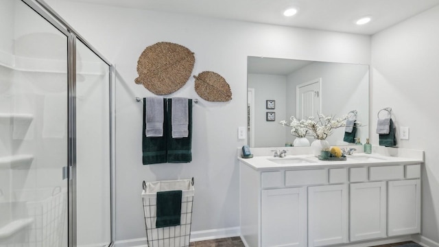 full bathroom with a stall shower, double vanity, baseboards, and recessed lighting