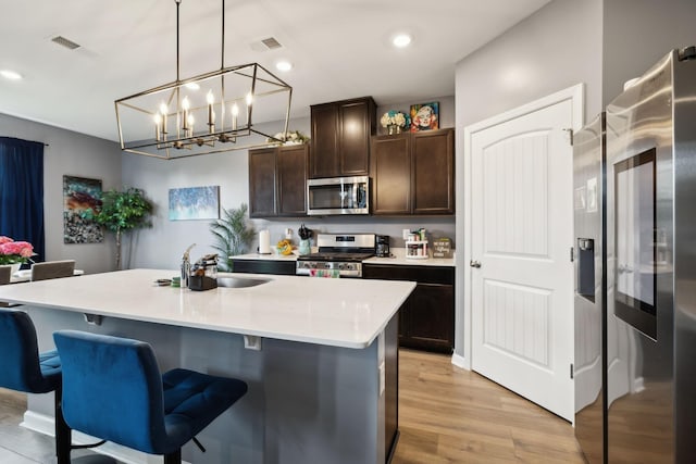 7401 Brady Ln, Antioch, TN 37013 - kitchen with stainless steel appliances, dark brown cabinets, light wood finished floors, a chandelier, and light countertops