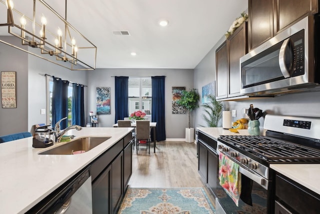 7401 Brady Ln, Antioch, TN 37013 - kitchen with appliances with stainless steel finishes, a sink, light countertops, light wood finished floors, and dark brown cabinetry