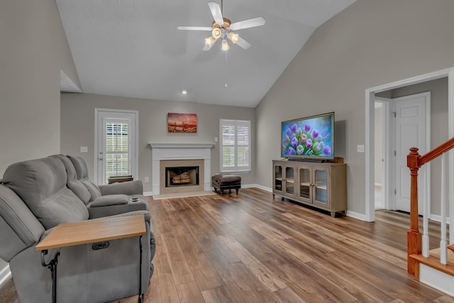 living area featuring ceiling fan, stairs, high vaulted ceiling, plenty of natural light, and a premium fireplace