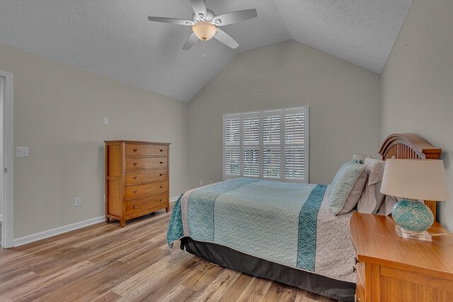 bedroom with lofted ceiling, light wood-style flooring, baseboards, and ceiling fan