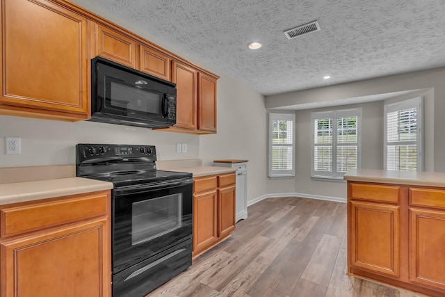 kitchen with black appliances, light wood-style floors, light countertops, a textured ceiling, and brown cabinets