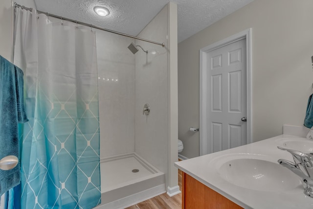 full bathroom with a shower with curtain, wood finished floors, a textured ceiling, double vanity, and toilet