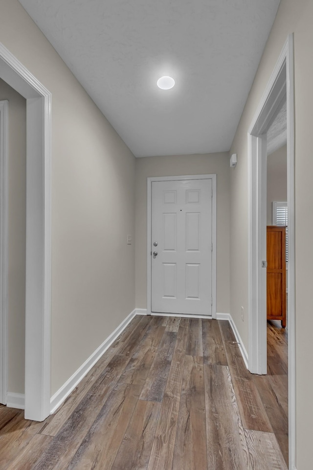 hall with wood-type flooring and baseboards