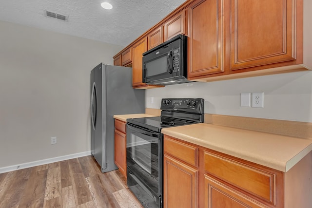 kitchen with black appliances, brown cabinetry, light wood-style flooring, light countertops, and baseboards