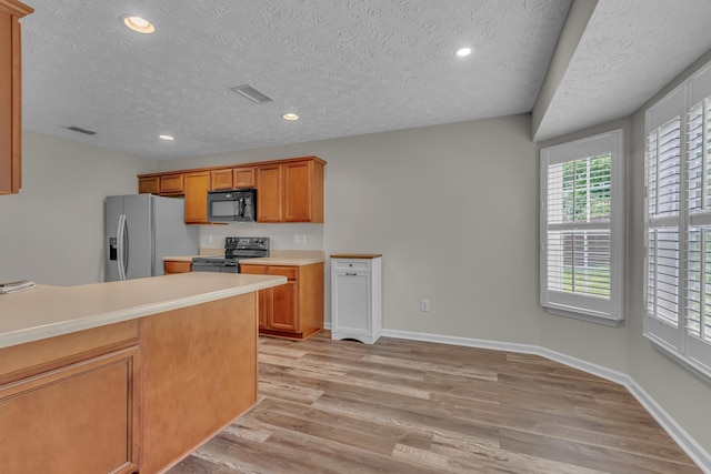 kitchen with black appliances, a textured ceiling, light wood-style floors, light countertops, and brown cabinets