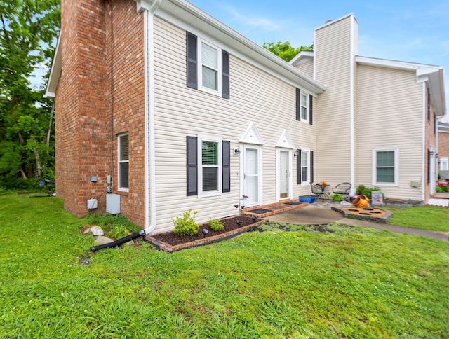 back of house featuring a chimney, a yard, and a patio