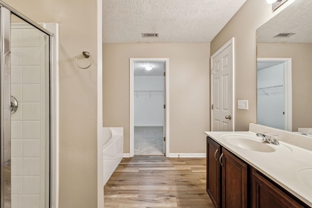 107 Owl Dr, Lebanon, TN 37087 - bathroom with wood finished floors, a stall shower, a garden tub, a walk in closet, and a textured ceiling