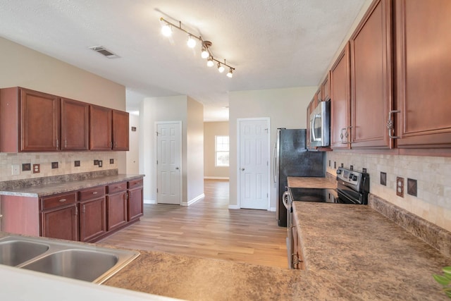 107 Owl Dr, Lebanon, TN 37087 - kitchen featuring appliances with stainless steel finishes, light wood-style floors, a textured ceiling, backsplash, and baseboards