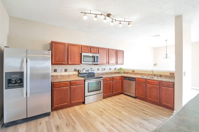 107 Owl Dr, Lebanon, TN 37087 - kitchen with stainless steel appliances, a sink, light wood-style floors, brown cabinets, and tasteful backsplash