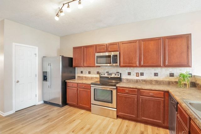 107 Owl Dr, Lebanon, TN 37087 - kitchen featuring stainless steel appliances, light wood finished floors, tasteful backsplash, and brown cabinetry