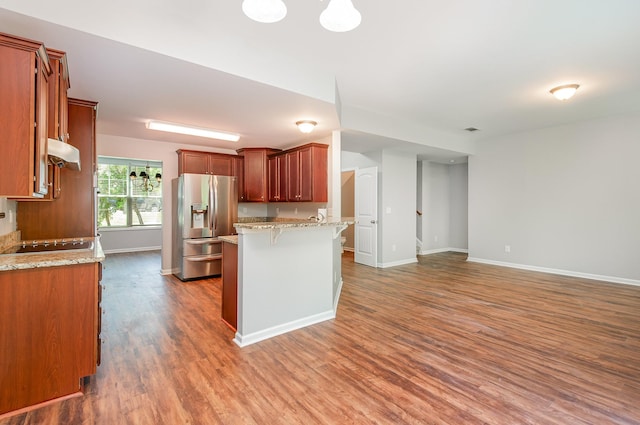 8007 Timber Cove Dr, Mount Juliet, TN 37122 - kitchen featuring stainless steel fridge with ice dispenser, a peninsula, wood finished floors, under cabinet range hood, and a kitchen breakfast bar