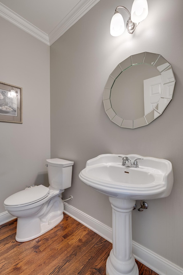 half bath featuring ornamental molding, wood finished floors, toilet, and baseboards
