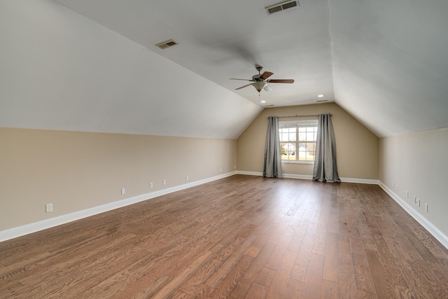 additional living space with dark wood-style floors, lofted ceiling, ceiling fan, and baseboards