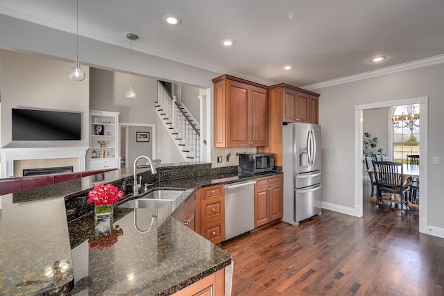 kitchen with appliances with stainless steel finishes, a sink, ornamental molding, brown cabinets, and recessed lighting