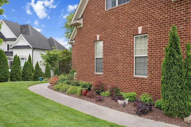 view of home's exterior with brick siding and a lawn