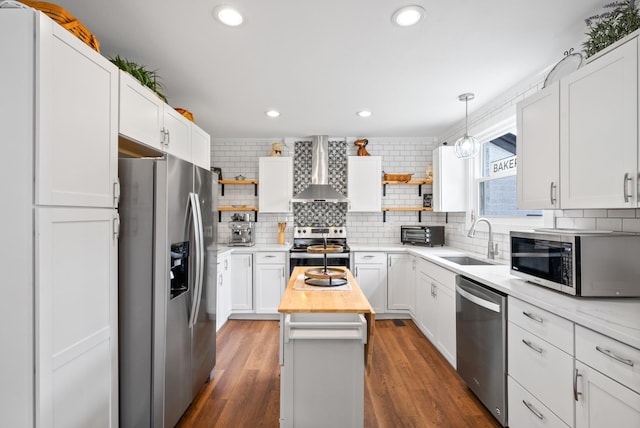 kitchen featuring wall chimney range hood, appliances with stainless steel finishes, open shelves, a sink, and decorative backsplash