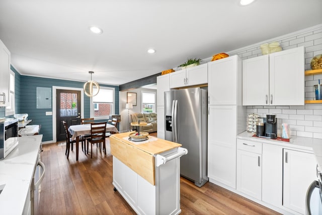 kitchen with stainless steel fridge, healthy amount of natural light, white cabinetry, ornamental molding, and recessed lighting