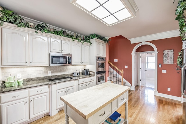 131 Grandview Cir, Gallatin, TN 37066 - kitchen featuring appliances with stainless steel finishes, backsplash, white cabinetry, arched walkways, and crown molding