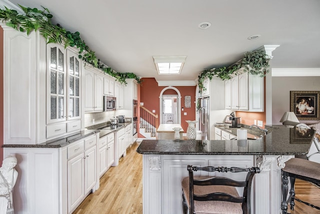 131 Grandview Cir, Gallatin, TN 37066 - kitchen featuring stainless steel appliances, a breakfast bar area, light wood finished floors, glass insert cabinets, and dark stone countertops
