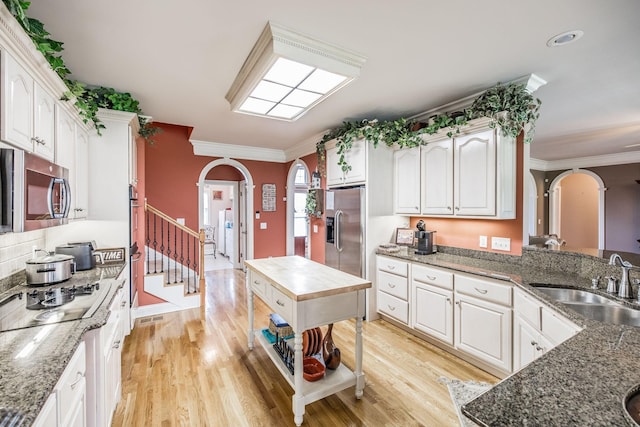 131 Grandview Cir, Gallatin, TN 37066 - kitchen with arched walkways, stainless steel appliances, a sink, crown molding, and light wood-style floors